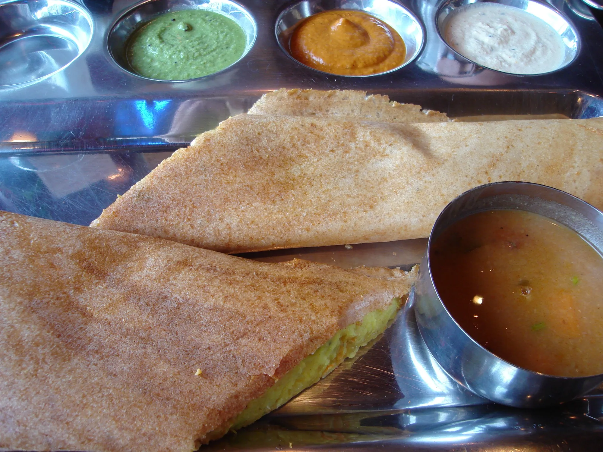 A masala dosa served with sambar and chutneys
